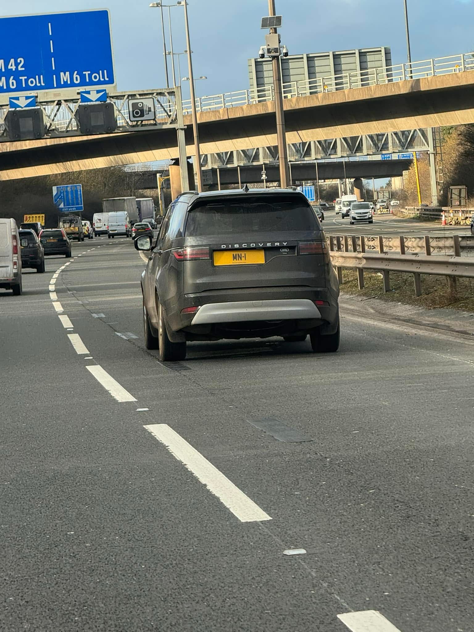 Rear view of a dark Land Rover Discovery displaying the yellow registration plate MN 1
